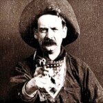 Great_train_robbery_Barnes A man dressed as a cowboy wears a wide-brimmed hat and a bandana around his neck. He has a stern expression and a thick mustache and is aiming a revolver directly at the camera, creating a dramatic and confrontational effect.